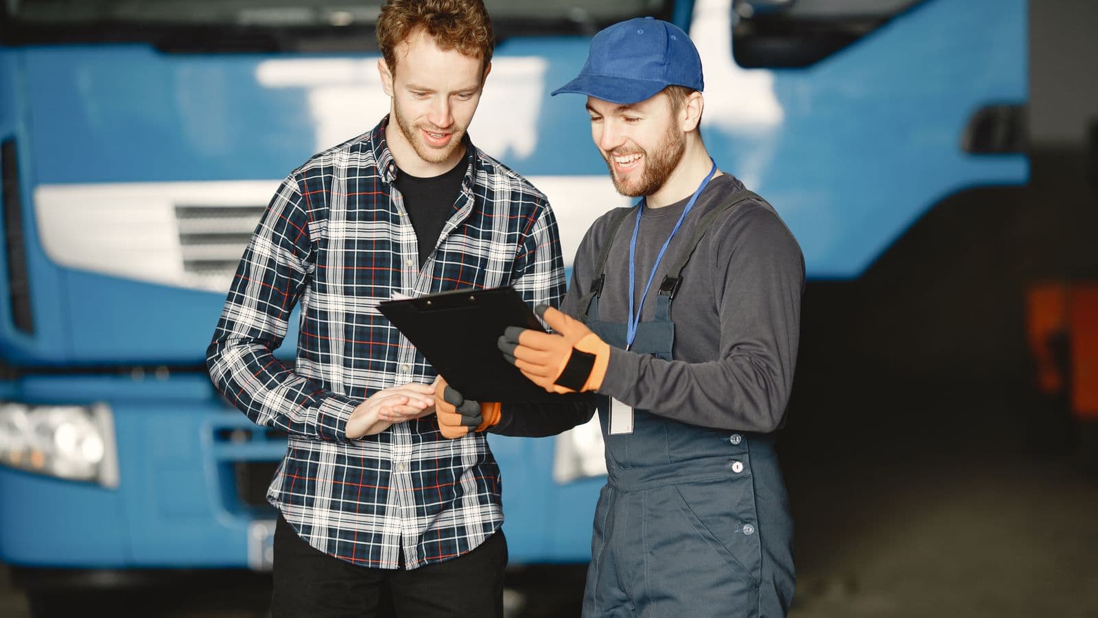 Two uniformed technicians reviewing paperwork in front of a service truck