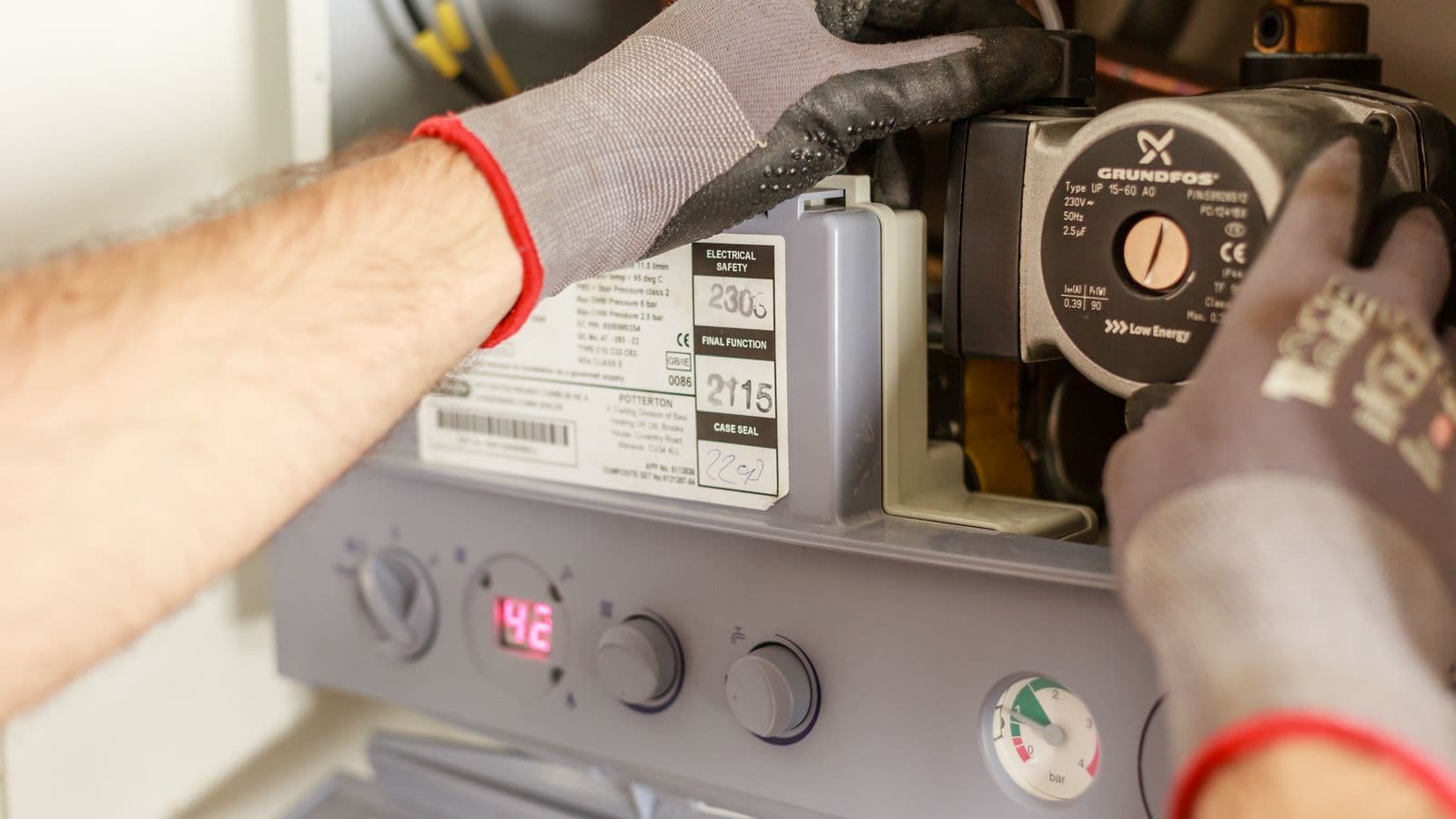 A technician's gloved hands servicing a gas boiler