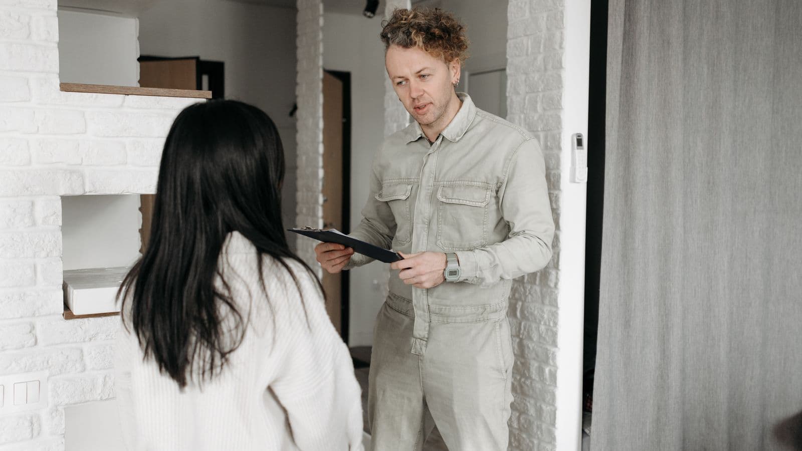 A home services technician reviewing a checklist with a homeowner inside their home